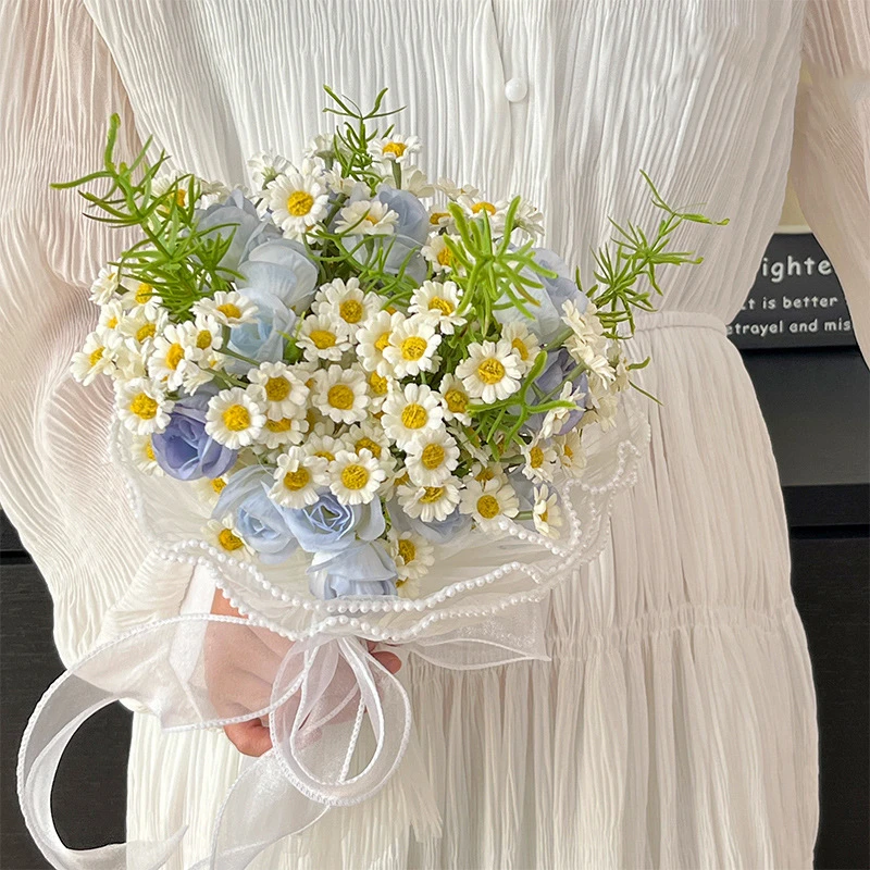 Daisy and blue artificial bridesmaid bouquet with a pearl-wrapped handle, held in one hand