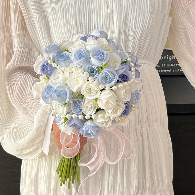 Dusty blue artificial bridesmaid bouquet with a pearl-wrapped handle, held in one hand