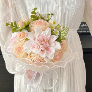 Nude pink artificial bridesmaid bouquet with a pearl-wrapped handle, held in one hand