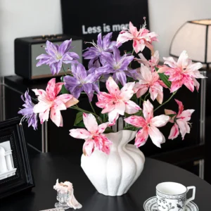 Artificial clematis stem with three open star-shaped flowers, styled in a room setting