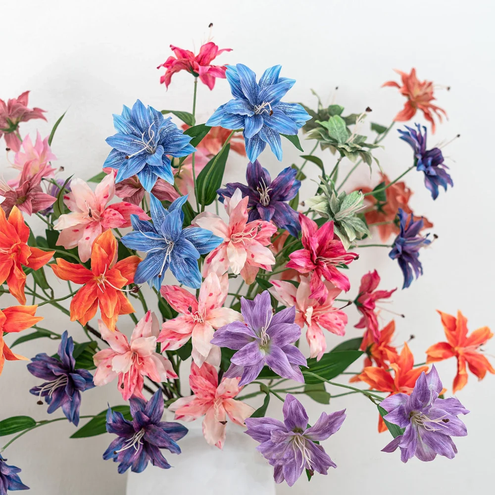 Artificial clematis stem with three open star-shaped flowers, styled on a table top