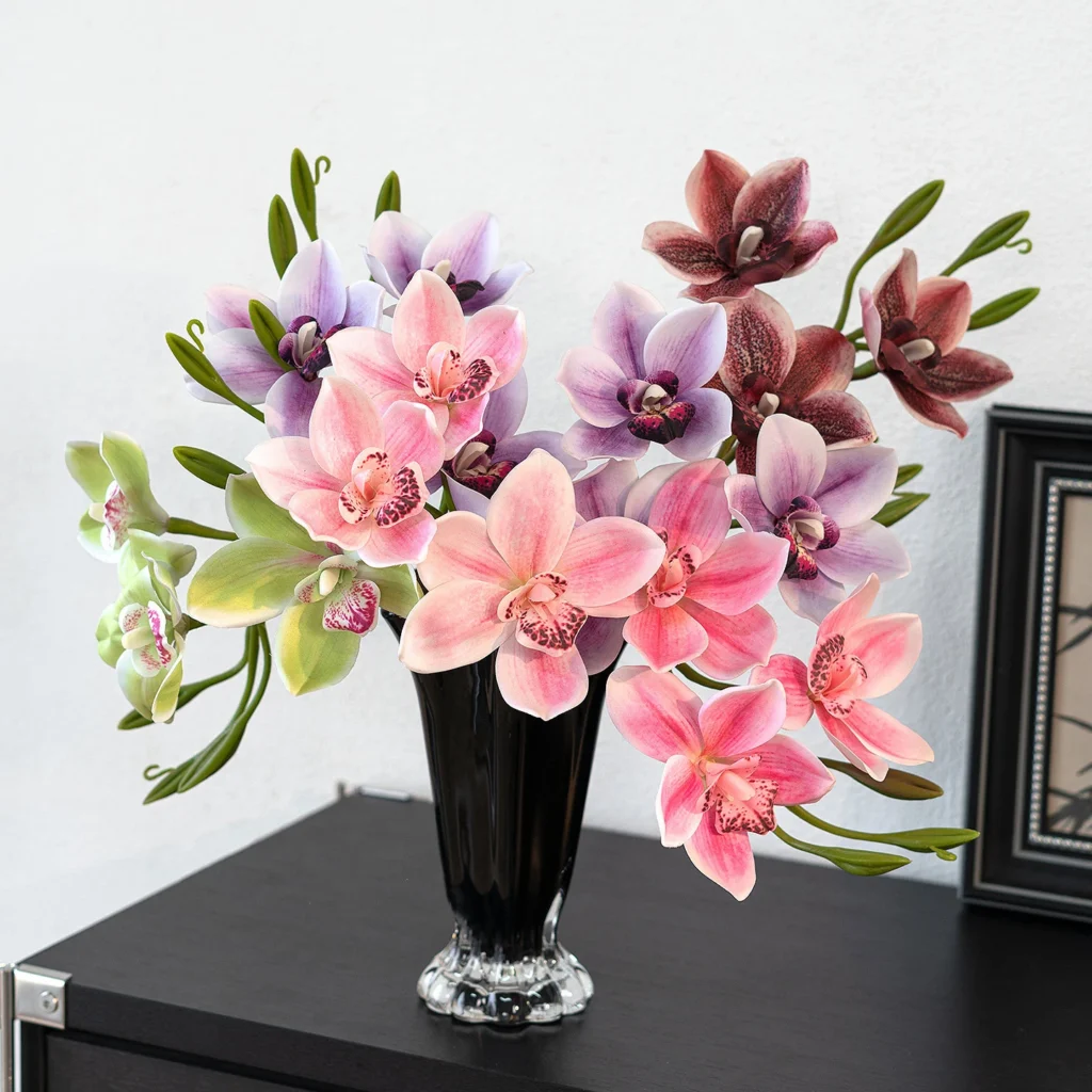 Artificial cymbidium orchid stem with several open blooms and buds along one arching cane, styled in a room setting