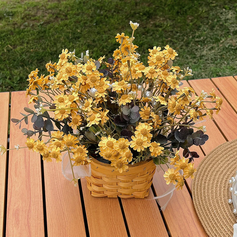 Yellow daisy artificial daisy plant in a basket massed into a dense dome, styled on a table top
