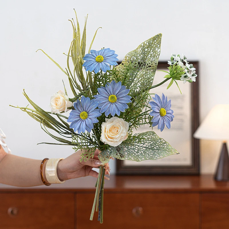 Blue daisy artificial daisy and skeleton leaf posy with lace-veined skeleton leaves, held in one hand