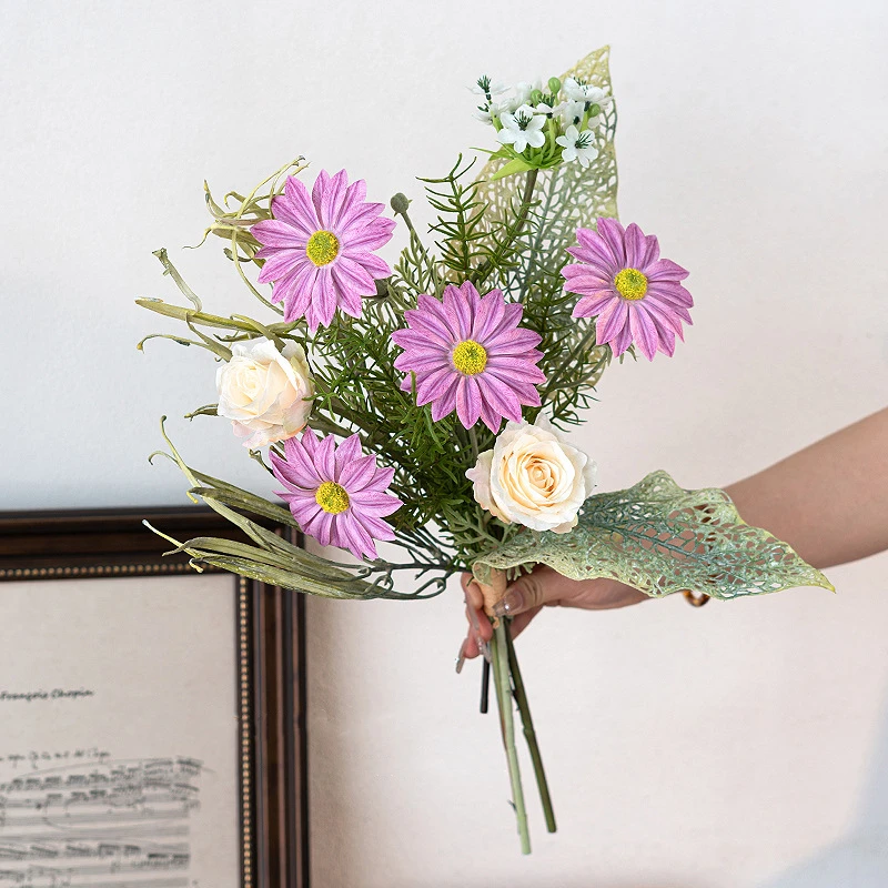 Magenta daisy artificial daisy and skeleton leaf posy with lace-veined skeleton leaves, held in one hand