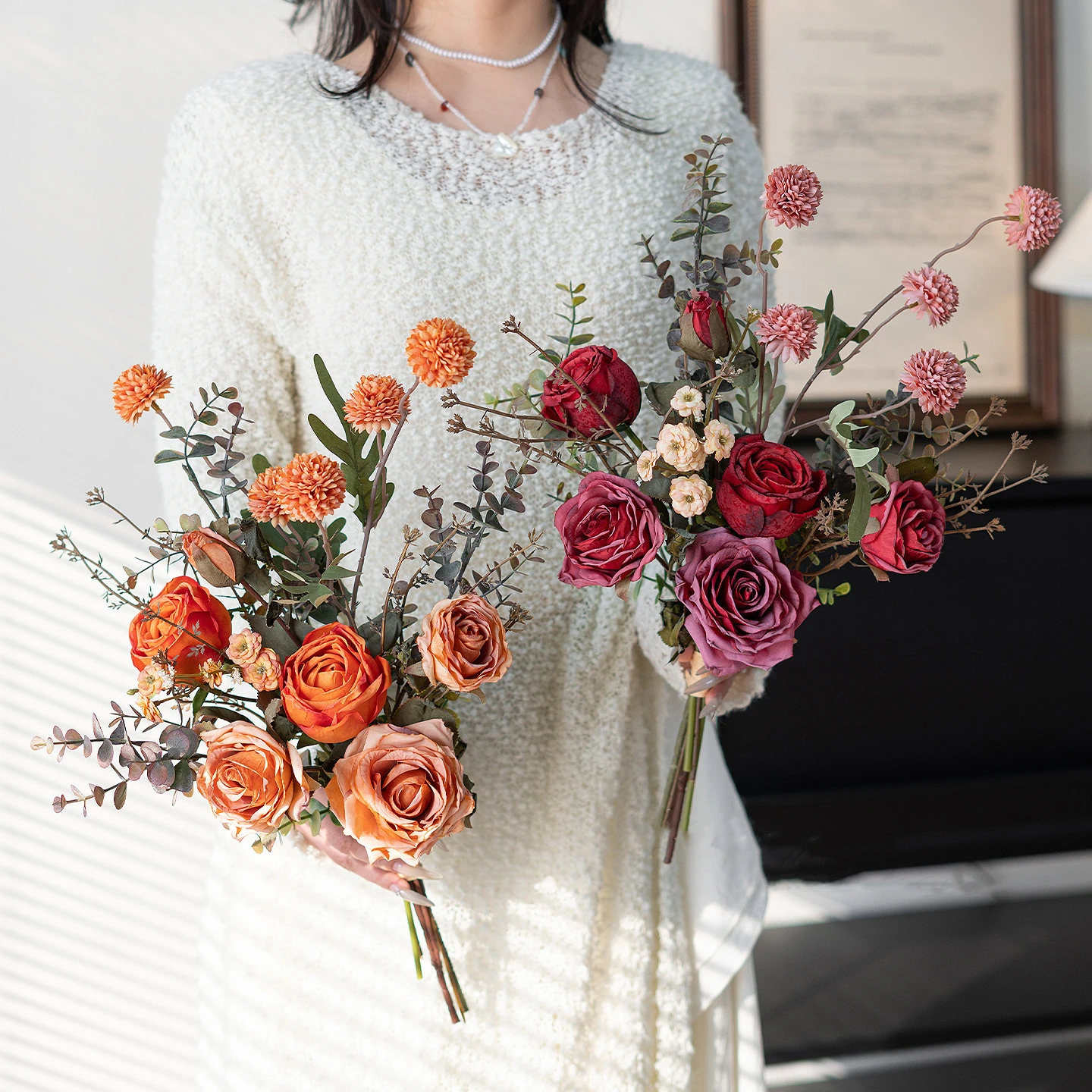 Orange artificial rose and eucalyptus bouquet built on a frame of eucalyptus stems, styled in a room setting