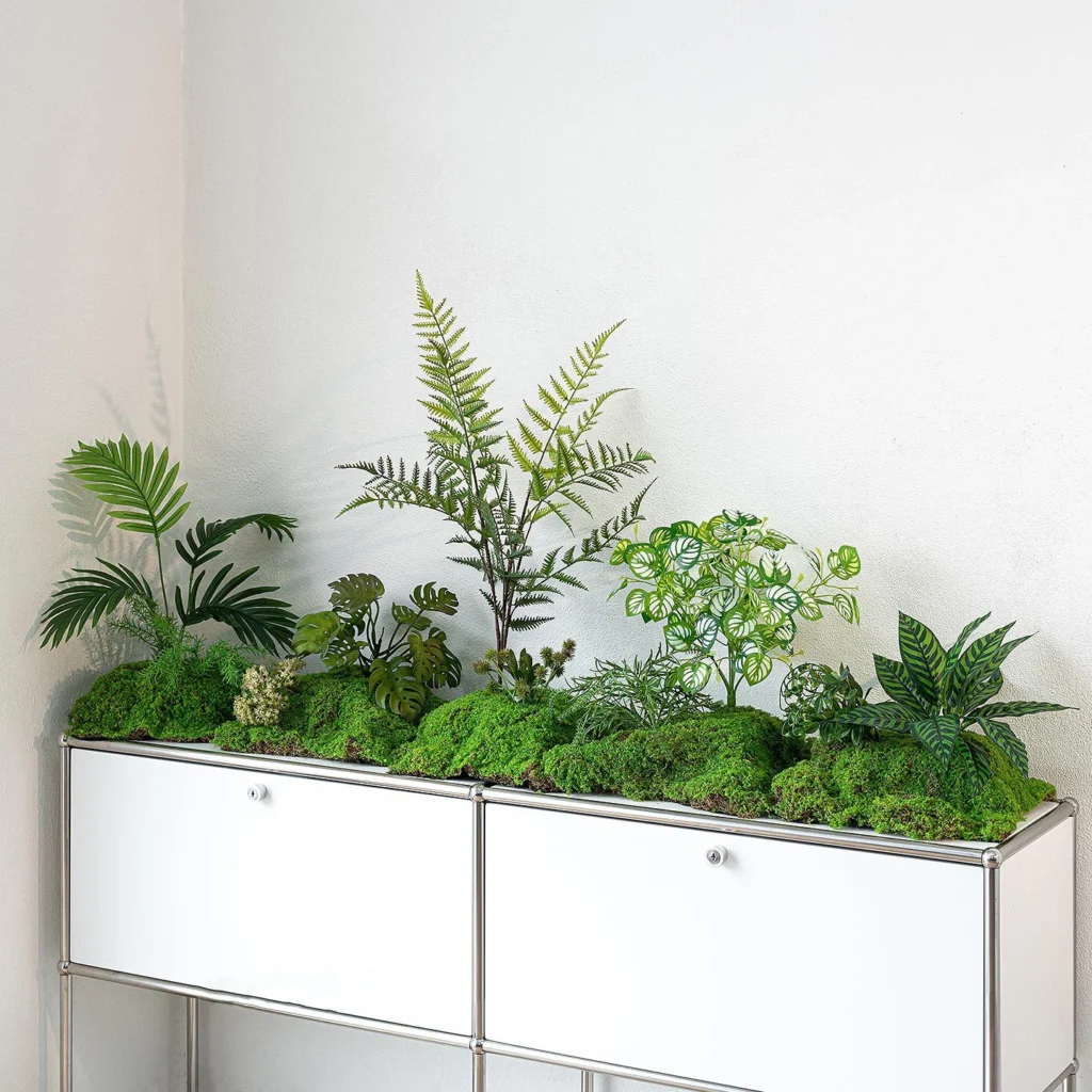 Artificial fern arrangement rooted into a raised moss mound, styled on a table top
