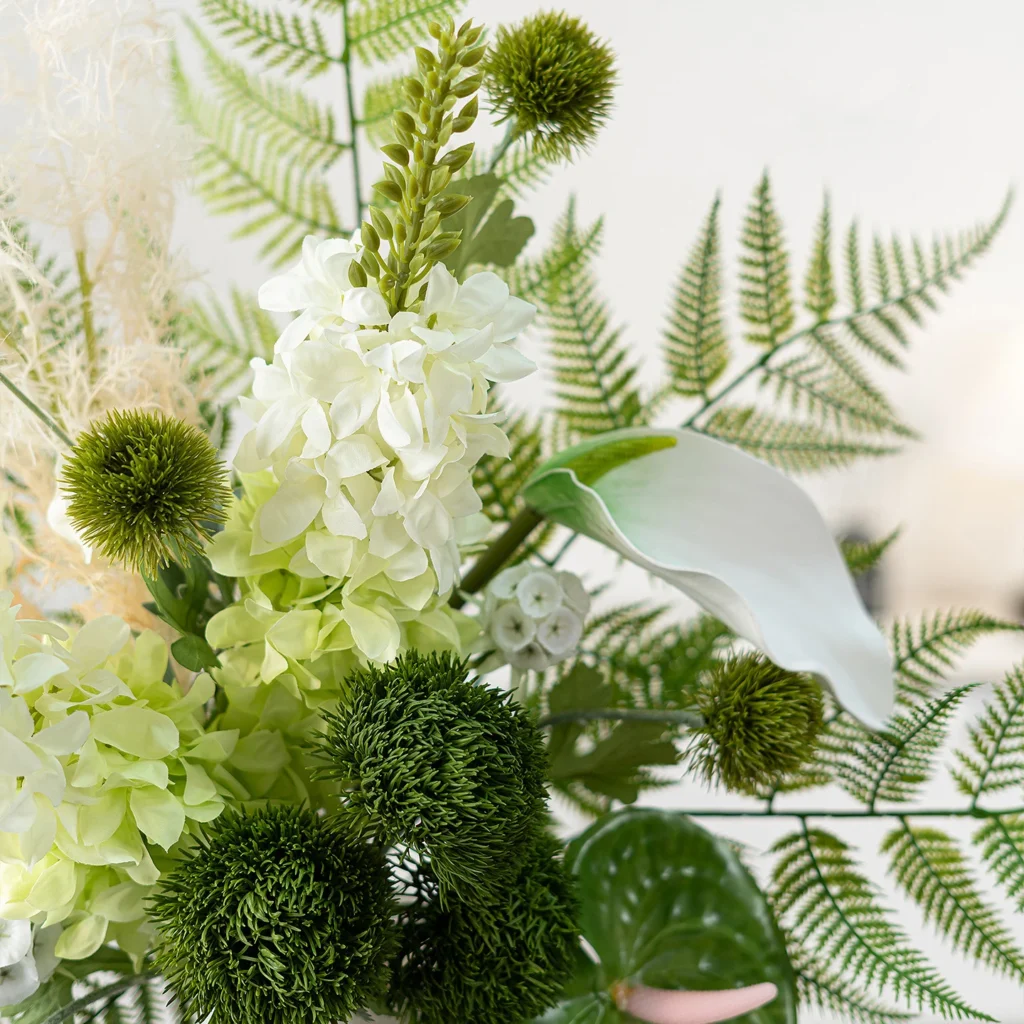 Artificial fern and flower bouquet built round a fan of fern fronds shown close up