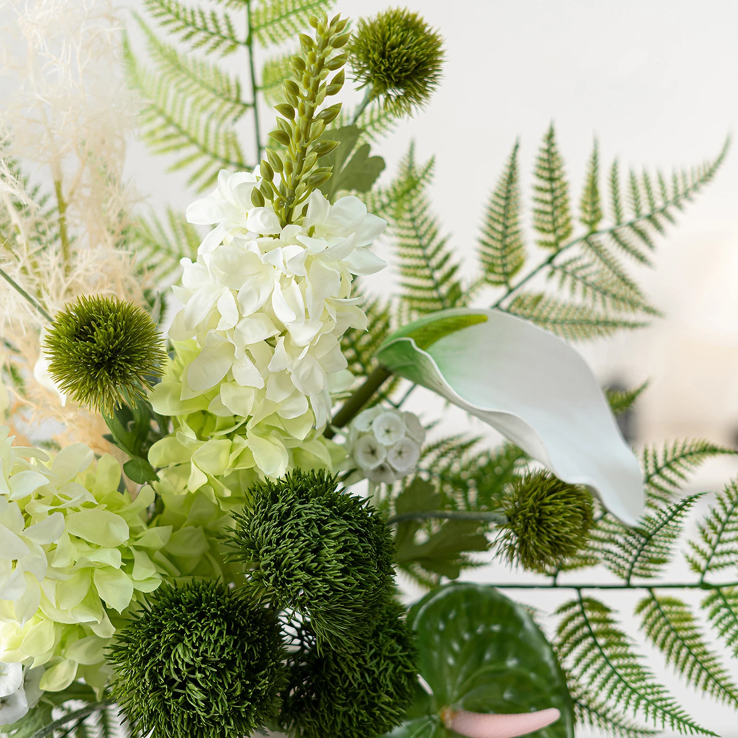 Artificial fern and flower bouquet built round a fan of fern fronds shown close up