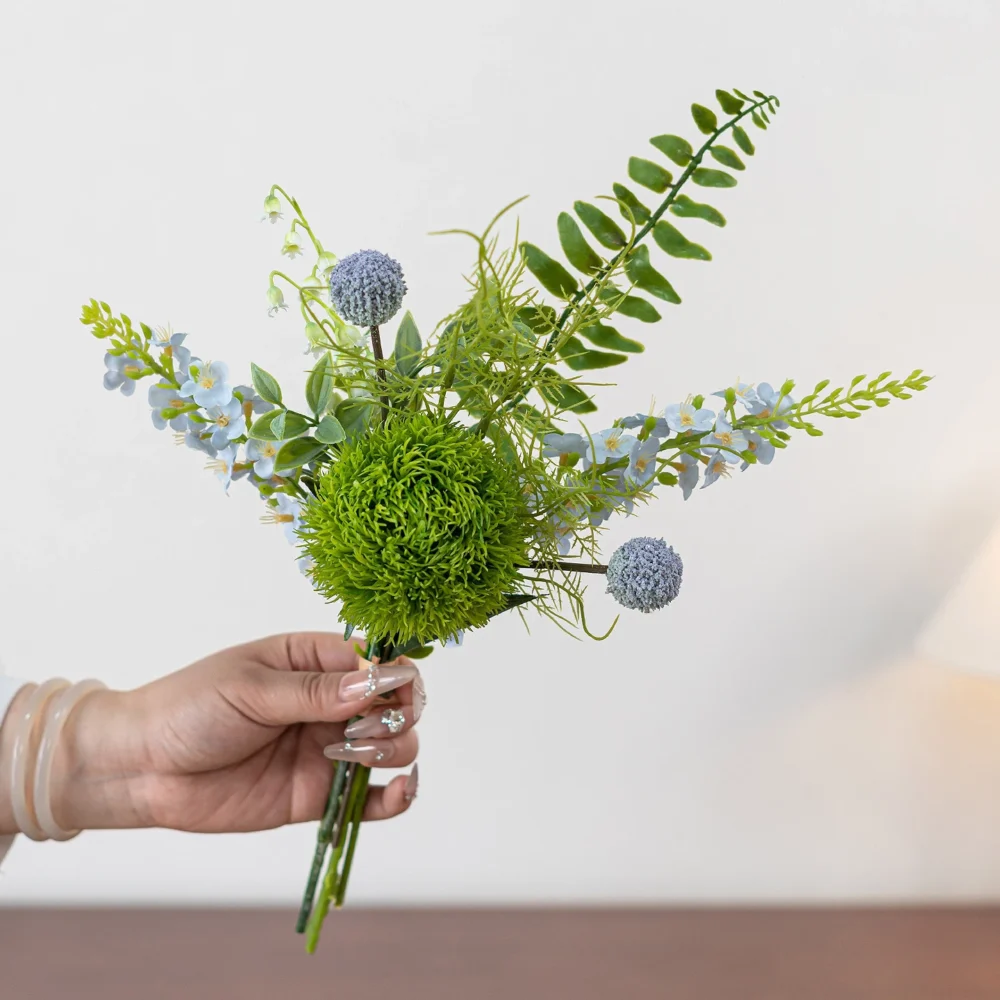 Blue artificial freesia and green dianthus posy built round one tight green dianthus head, held in one hand