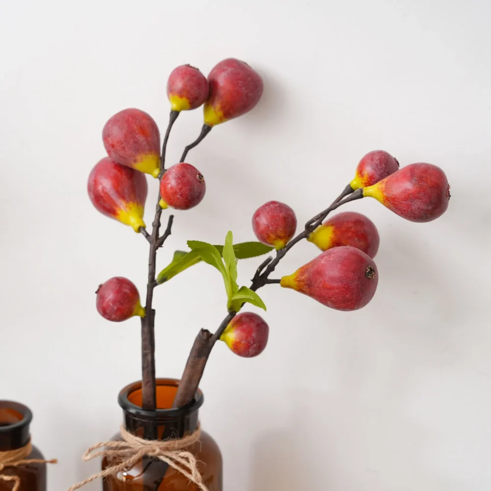 Red artificial fruit branch with figs and berries on a woody stem, arranged in a vase