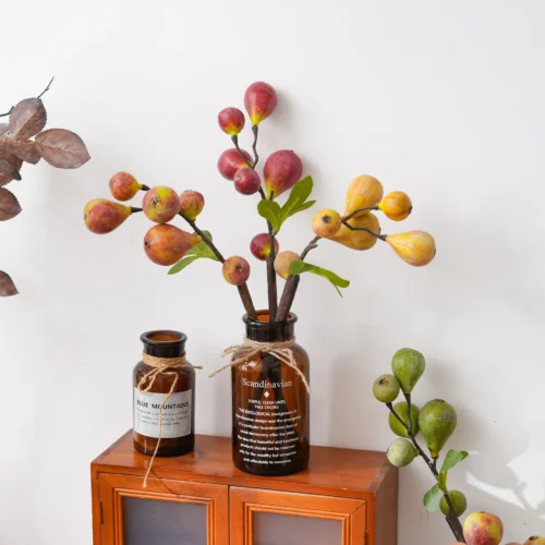 Artificial fruit branch with figs and berries on a woody stem, styled in a room setting