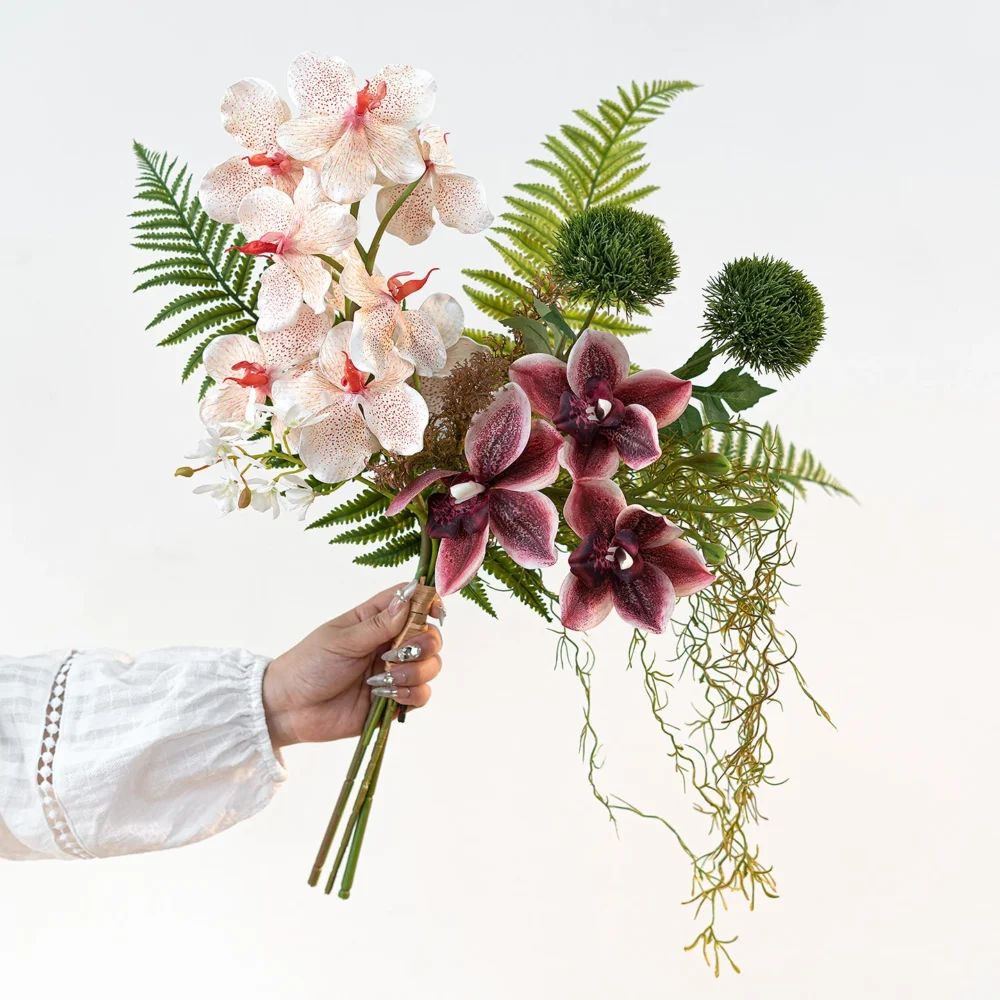 Blush and plum artificial hand tied orchid bouquet with ferns and trailing Spanish moss, held in one hand