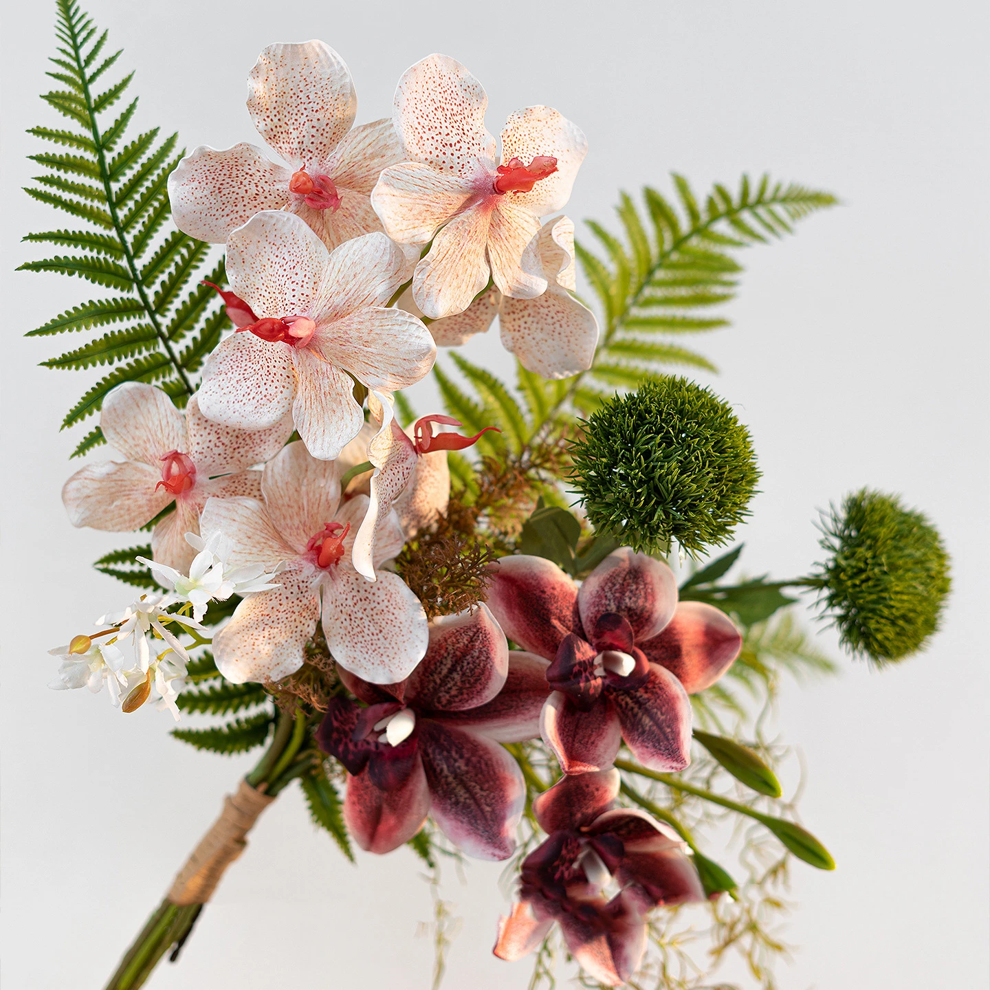 Peach and wine artificial hand tied orchid bouquet with ferns and trailing Spanish moss, held in one hand