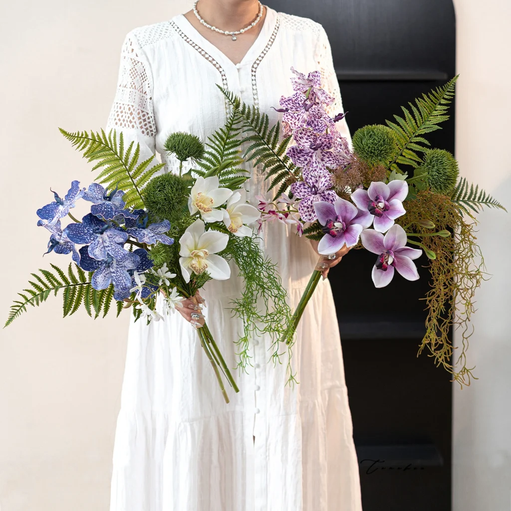 Artificial hand tied orchid bouquet with ferns and trailing Spanish moss, styled in a room setting