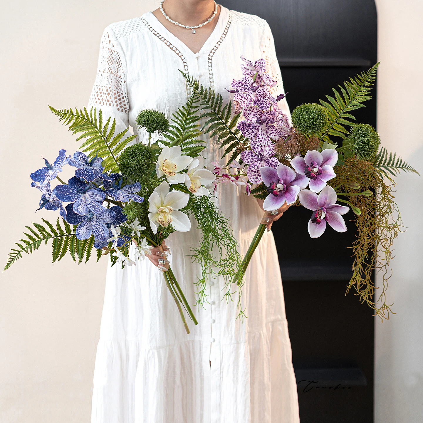 Artificial hand tied orchid bouquet with ferns and trailing Spanish moss, styled in a room setting