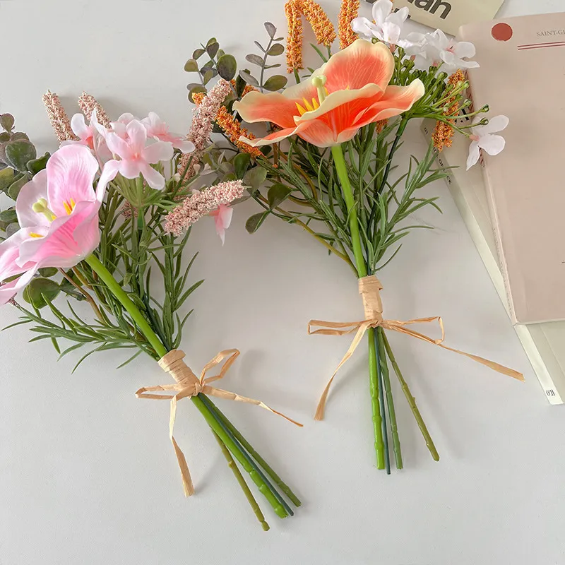 Coral artificial hibiscus flower bunch tied with raffia round one large trumpet bloom, styled on a table top