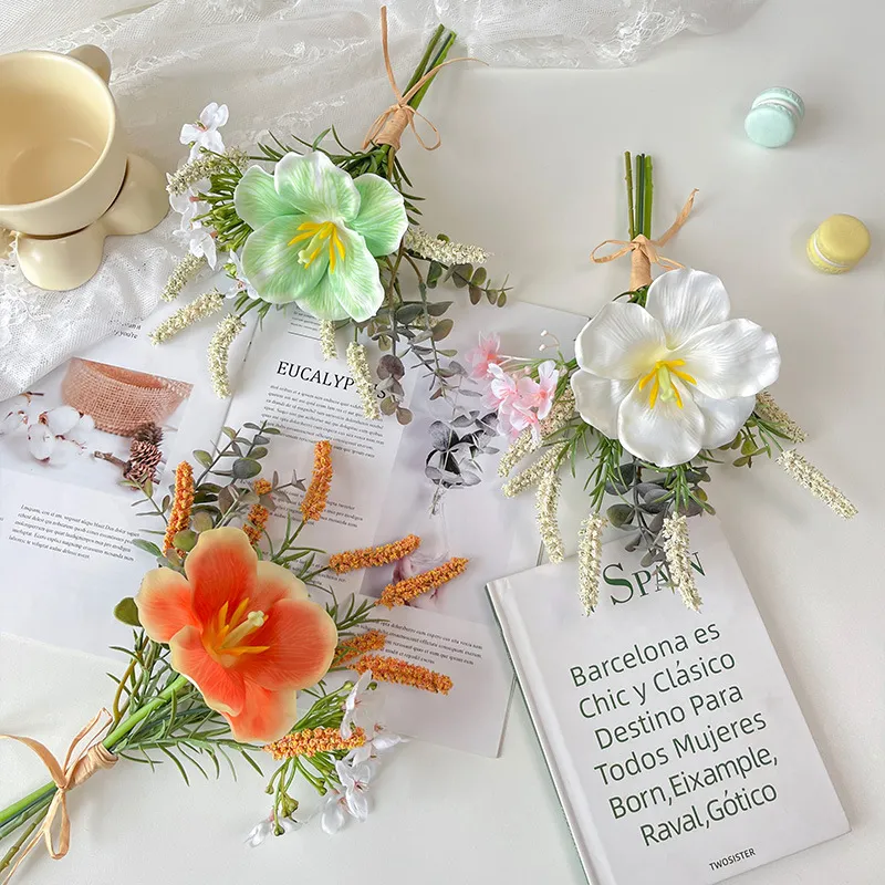 Artificial hibiscus flower bunch tied with raffia round one large trumpet bloom, styled on a table top