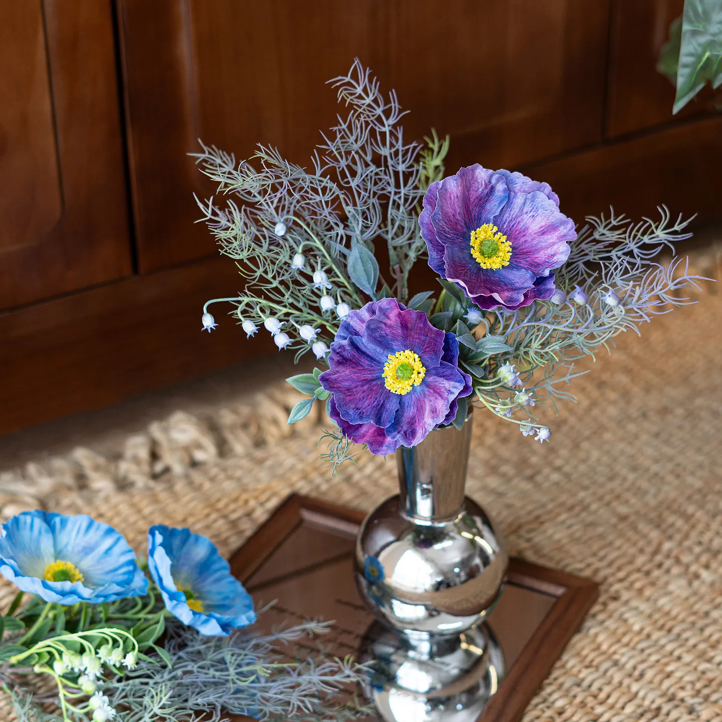 Purple artificial Iceland poppy stem with buds and fine fern foliage, arranged in a vase