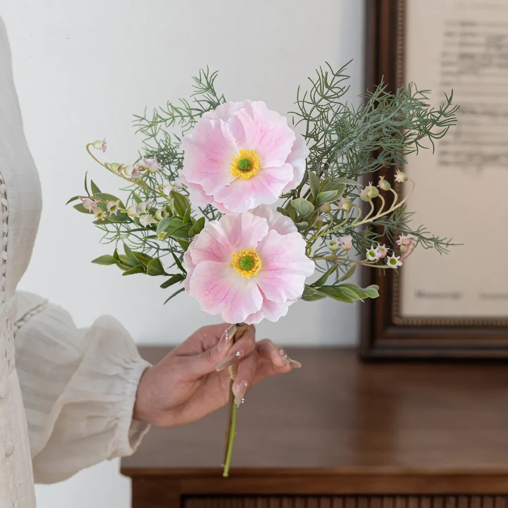 Soft pink artificial Iceland poppy stem with buds and fine fern foliage, held in one hand