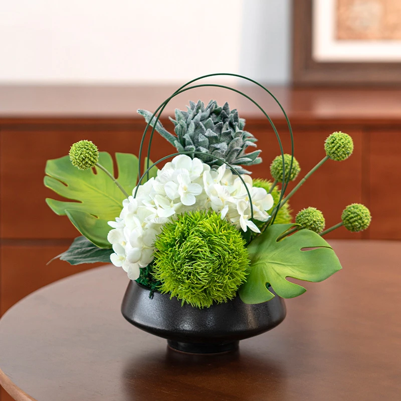 White hydrangea artificial ikebana arrangement in a low black bowl, styled on a table top