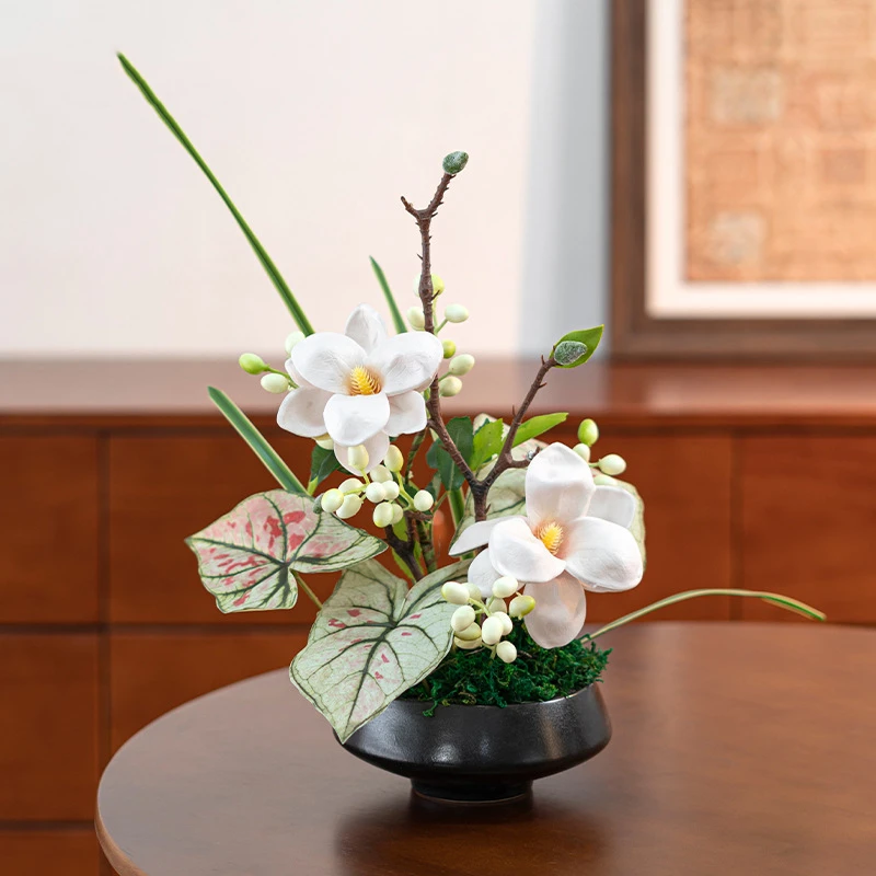 White magnolia artificial ikebana arrangement in a low black bowl, styled on a table top