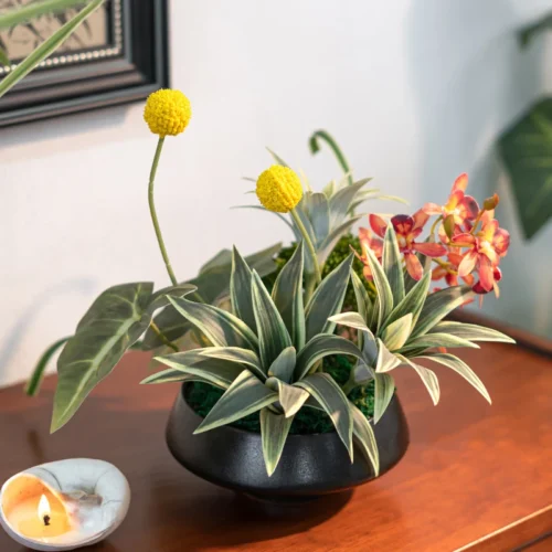 Yellow craspedia artificial ikebana arrangement in a low black bowl, styled on a table top