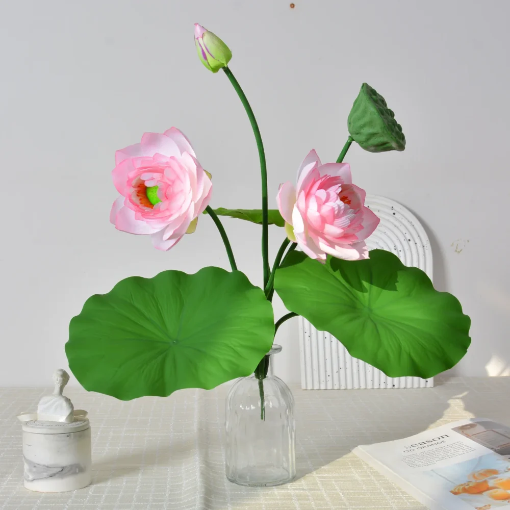 Blush artificial lotus flower arrangement with lotus pads, a seed head and buds, arranged in a vase