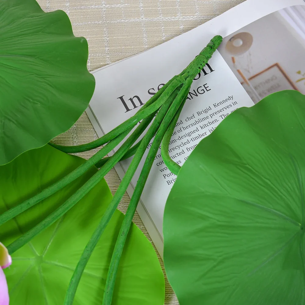 Artificial lotus flower arrangement with lotus pads, a seed head and buds shown close up
