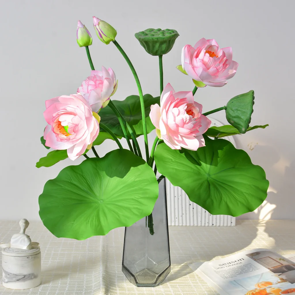 Pale pink artificial lotus flower arrangement with lotus pads, a seed head and buds, arranged in a vase
