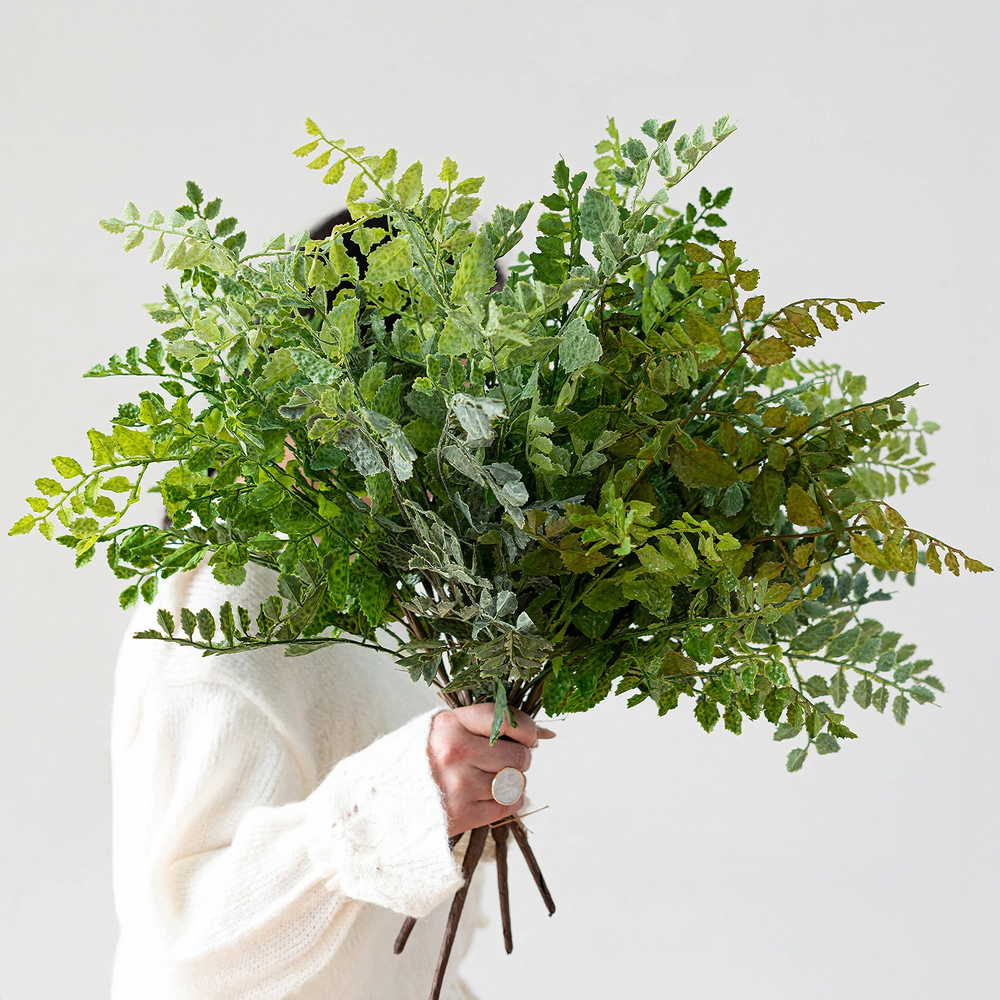 Mid green artificial maidenhair fern stem on fine black wire stems, held in one hand