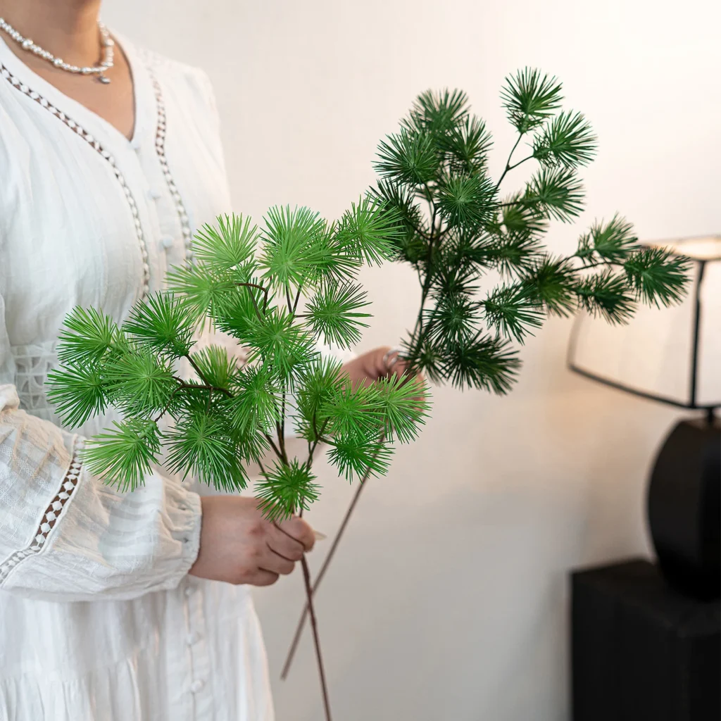 Artificial pine branch with soft needled side shoots on a brown stem shown close up