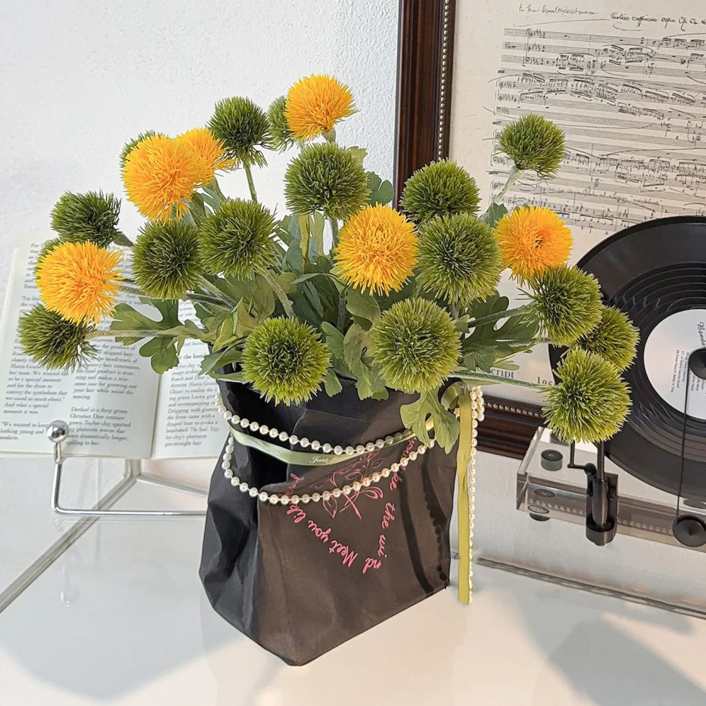 Artificial pompom chrysanthemum stem with a dense spiky head, styled in a room setting