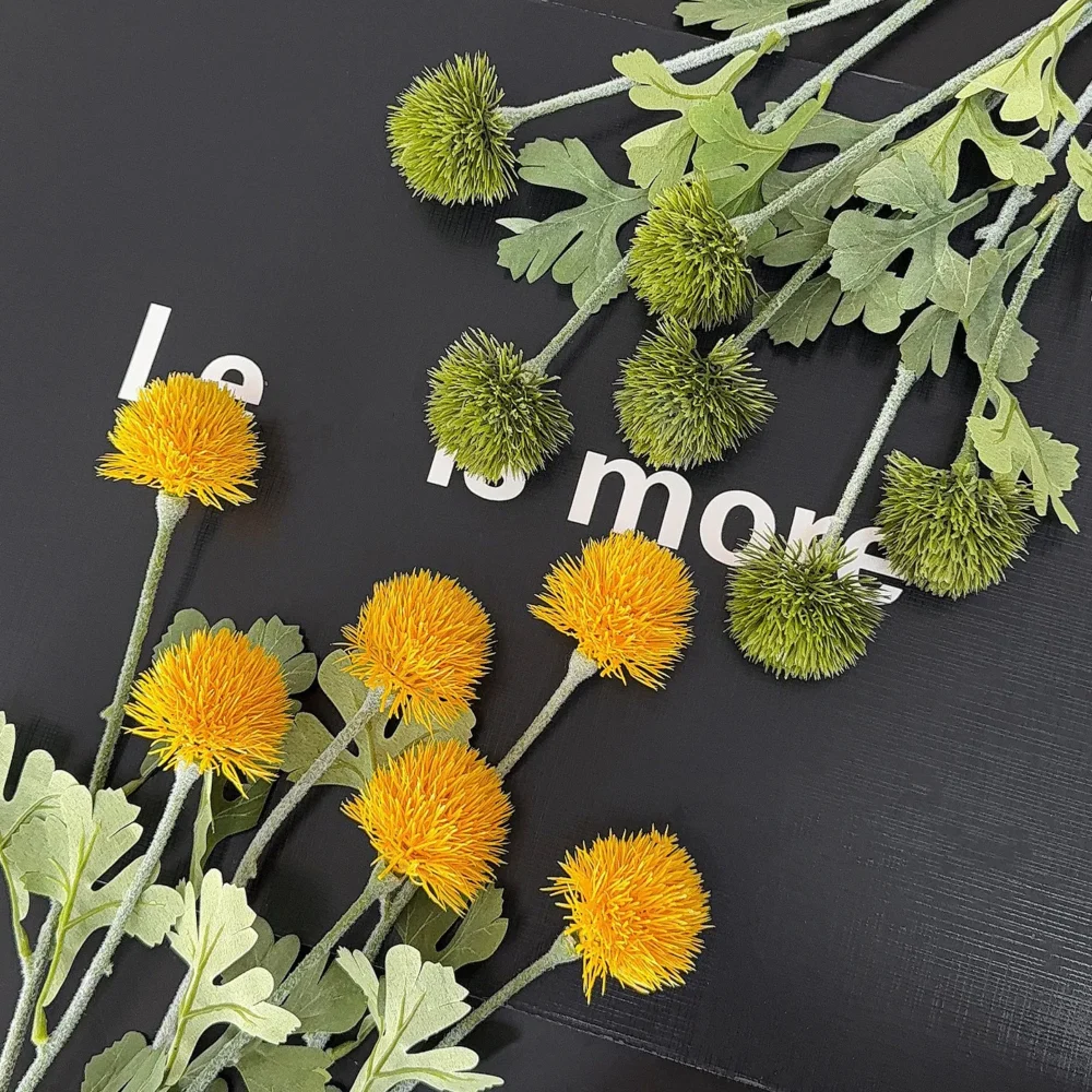 Artificial pompom chrysanthemum stem with a dense spiky head, styled on a table top
