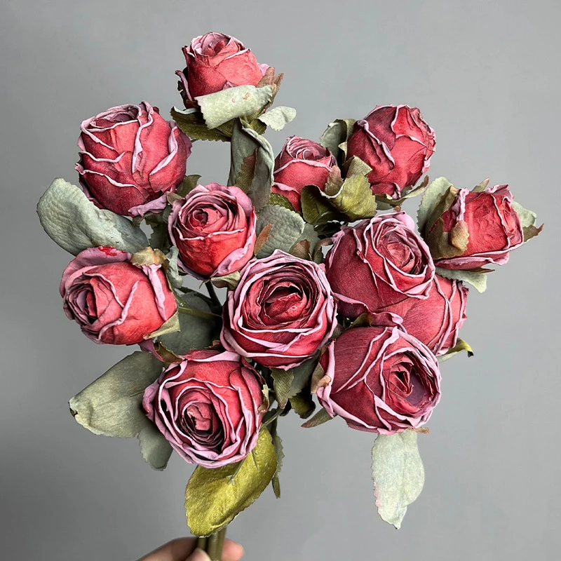 Cerise artificial rose bunch of twelve half-open buds on one tie, held in one hand