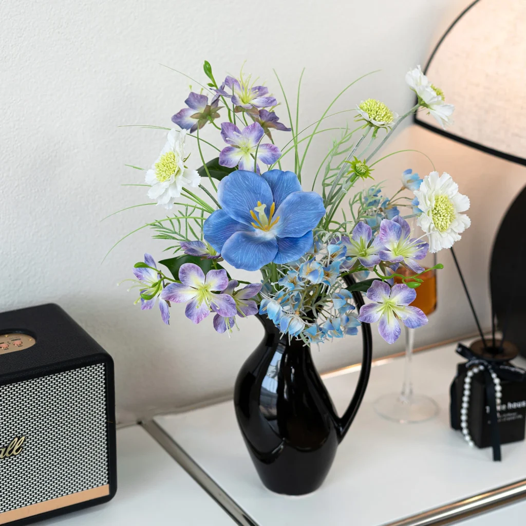 Cornflower blue artificial spring bouquet in blue and white of blue poppies, white blossom and fine grasses, styled in a room setting