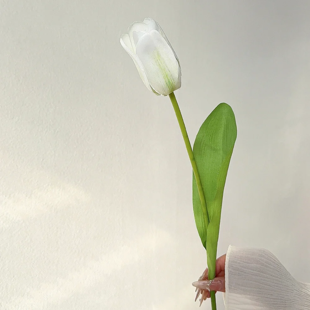 White artificial tulip bunch of ten stems, ten stems tied as a market bunch, held in one hand
