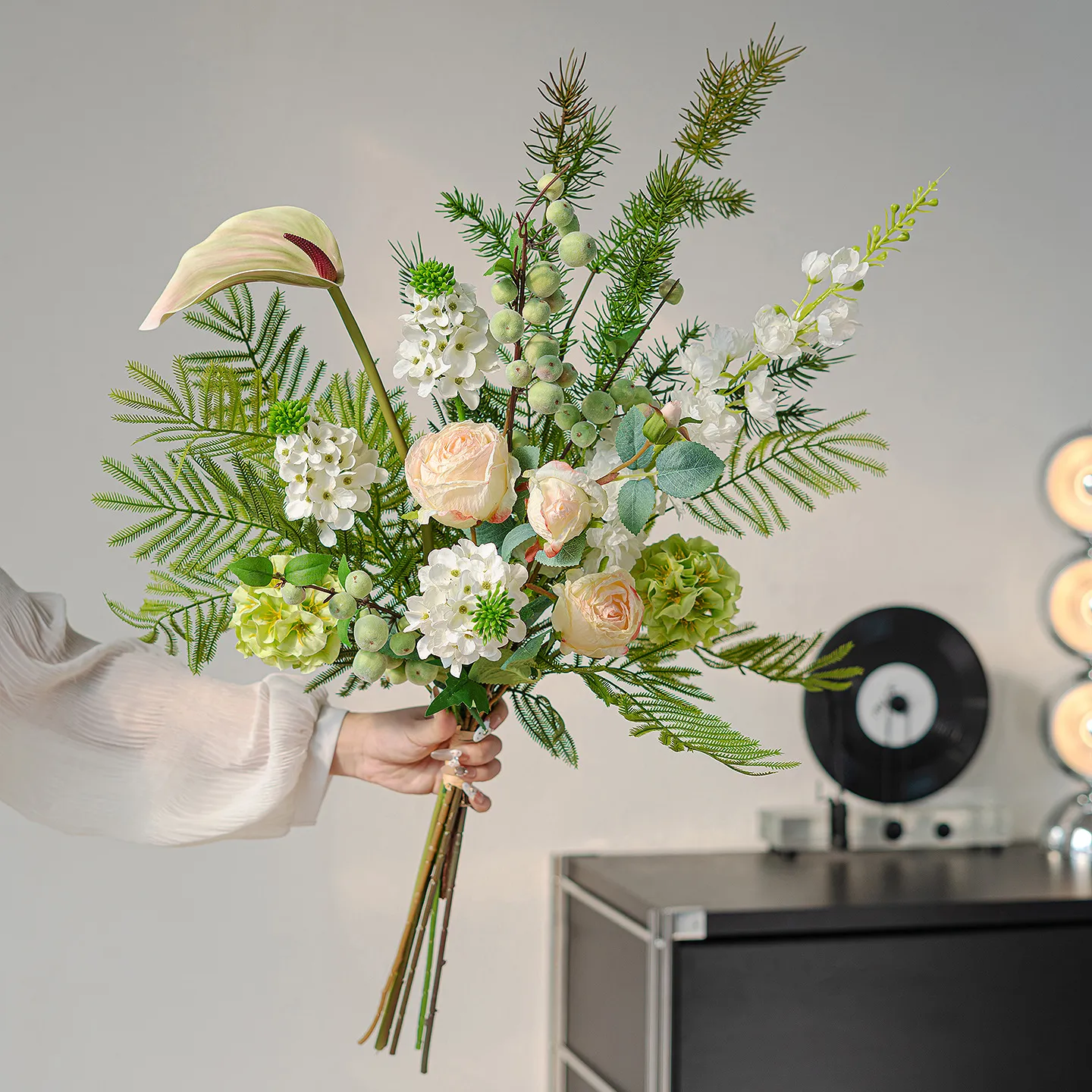 Cream and green botanical artificial flower bouquet of orchids, calla lilies, caladium leaves and ferns, held in one hand