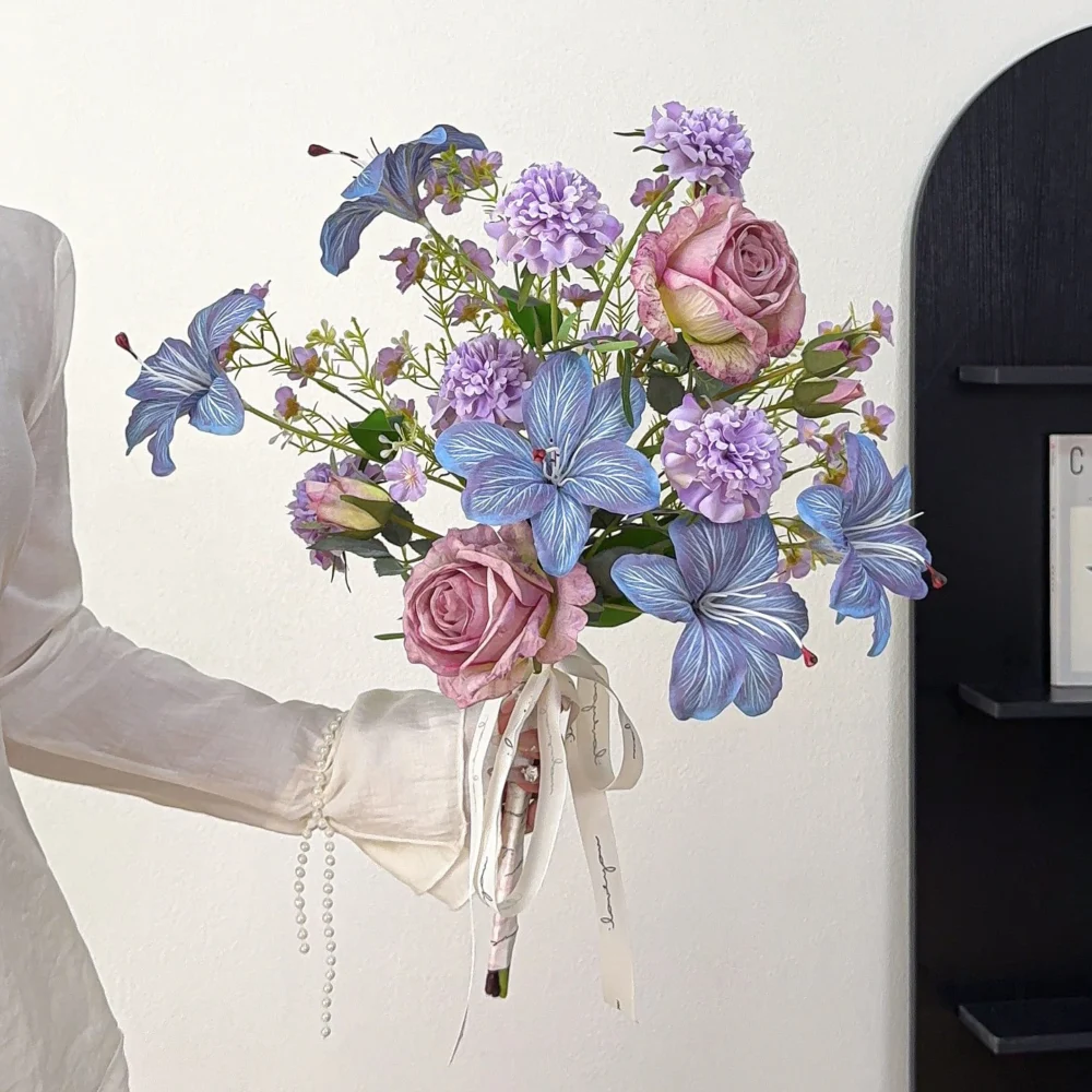 Mauve and blue artificial cascading wedding bouquet with a long trailing tail and ribbon, held in one hand