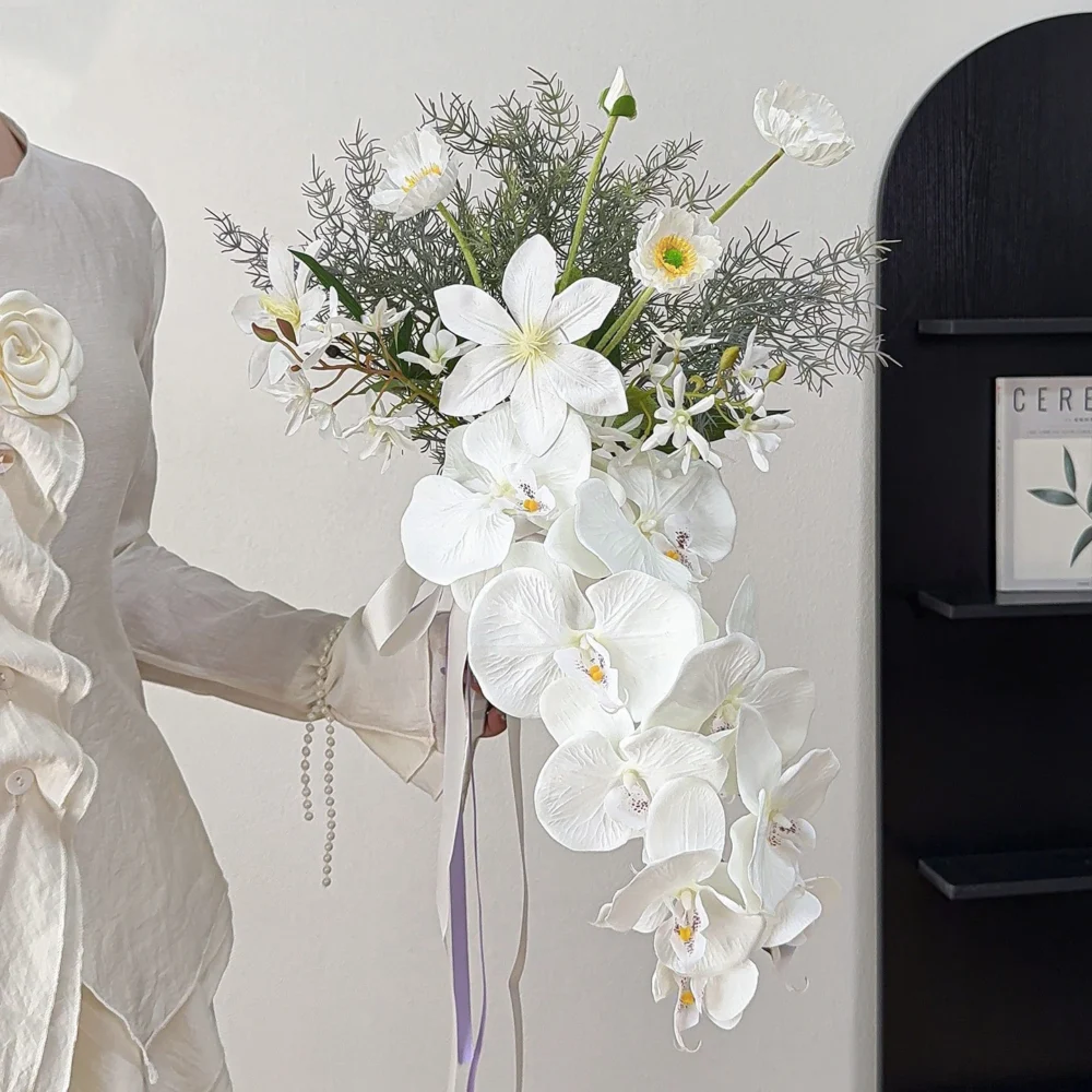 White orchid artificial cascading wedding bouquet with a long trailing tail and ribbon, held in one hand
