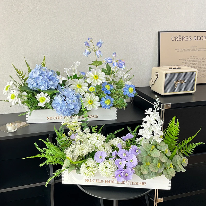 Blue and white artificial dining table centrepiece in a long white wooden trough, styled on a table top