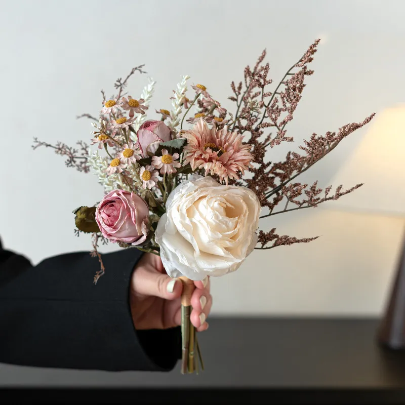 Ivory dried look artificial wedding bouquet of muted roses, seed heads and bare twigs, held in one hand