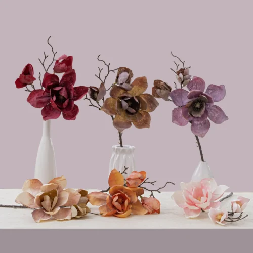 Dried look artificial magnolia stem on a bare twiggy branch, styled in a room setting