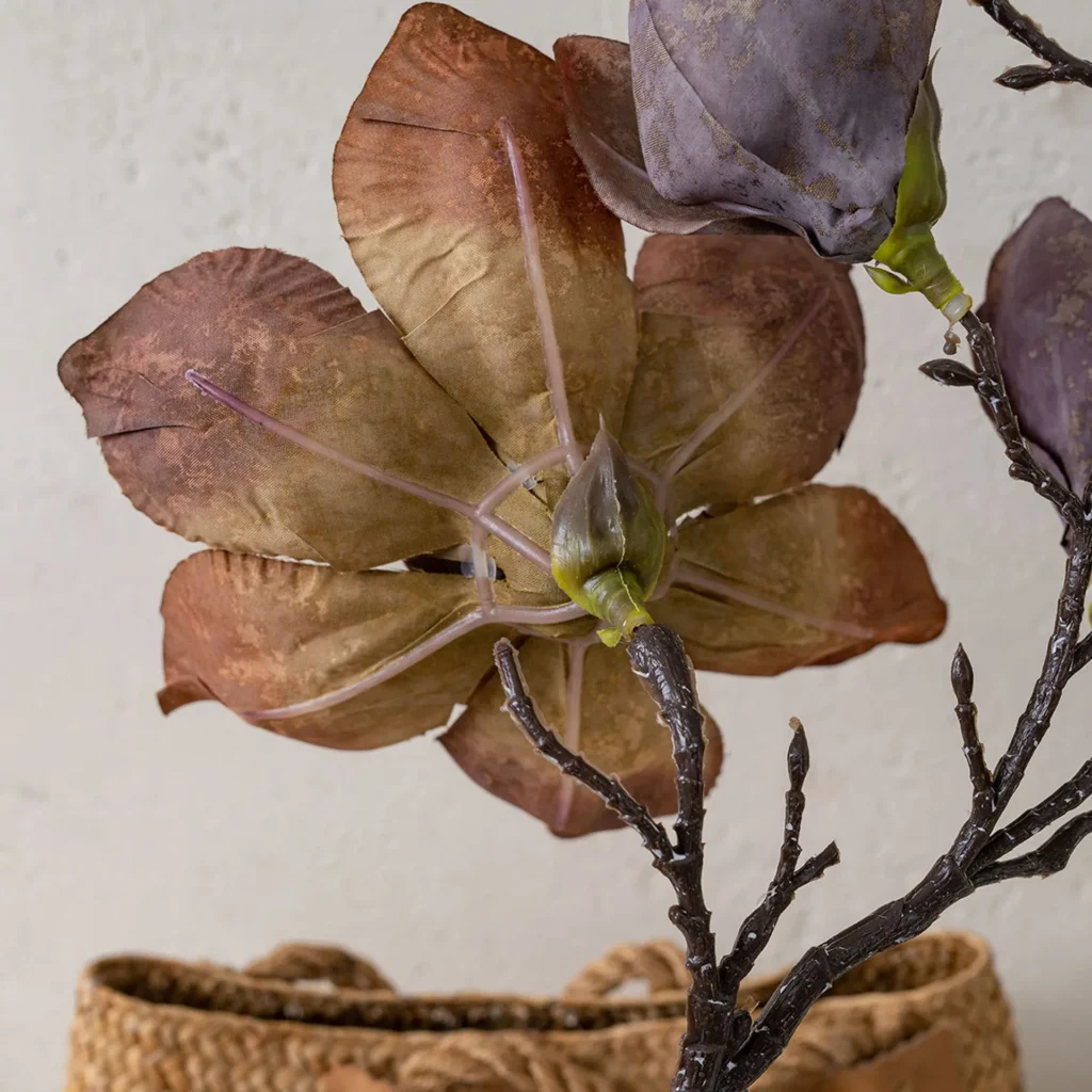 Taupe dried look artificial magnolia stem on a bare twiggy branch shown close up