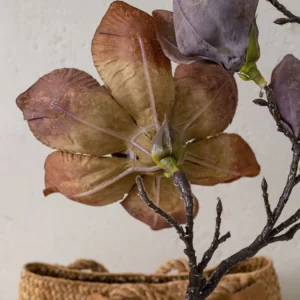 Taupe dried look artificial magnolia stem on a bare twiggy branch shown close up