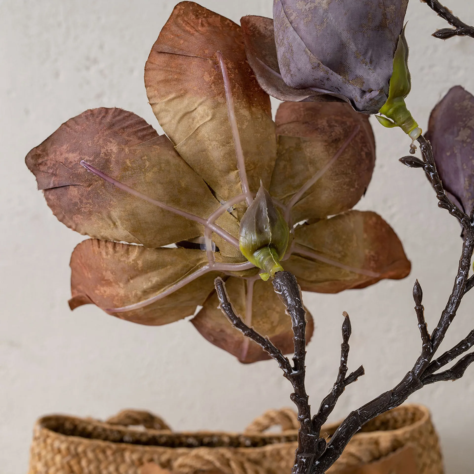 Artificial magnolia stem in faded rust and mauve on a dark knotted branch