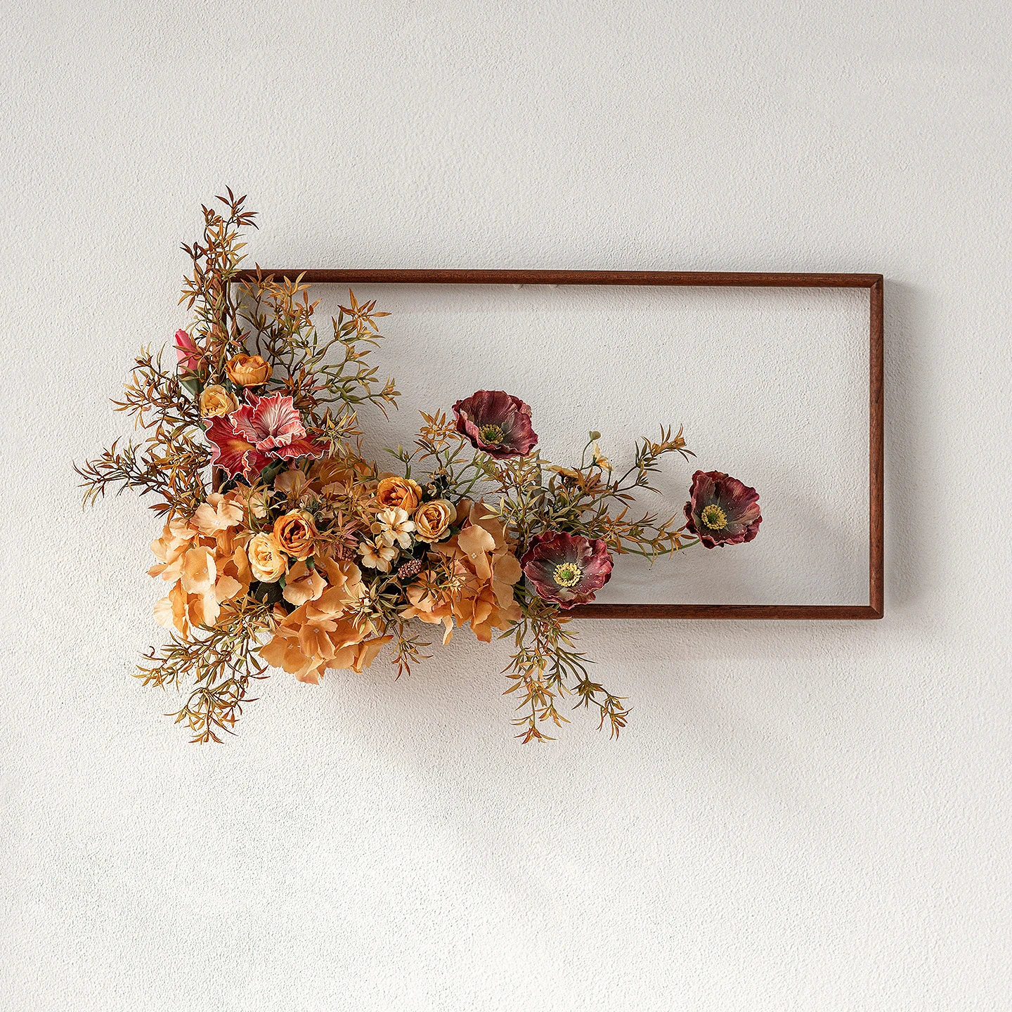 Floraler Wandrahmen mit künstlichen Blumen in warmen Herbsttönen