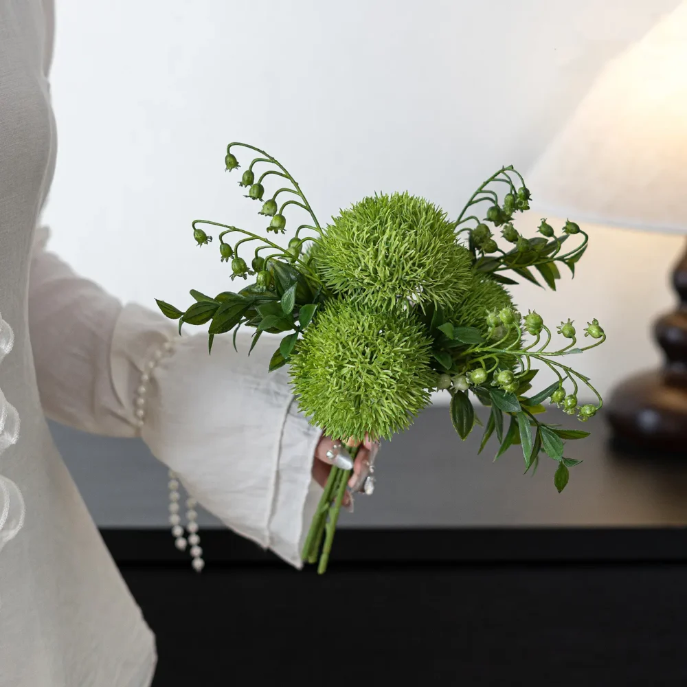Fern green artificial wedding bouquet of green dianthus balls and yellow billy buttons, held in one hand