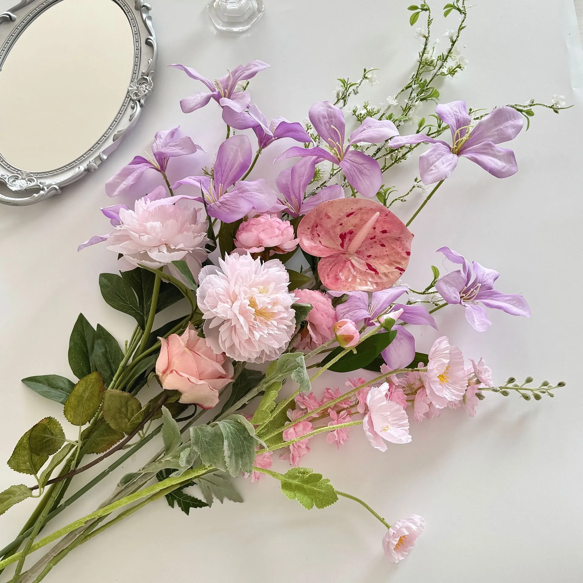 Lilac and pink large artificial flower bouquet of mixed silk spring blooms, styled on a table top