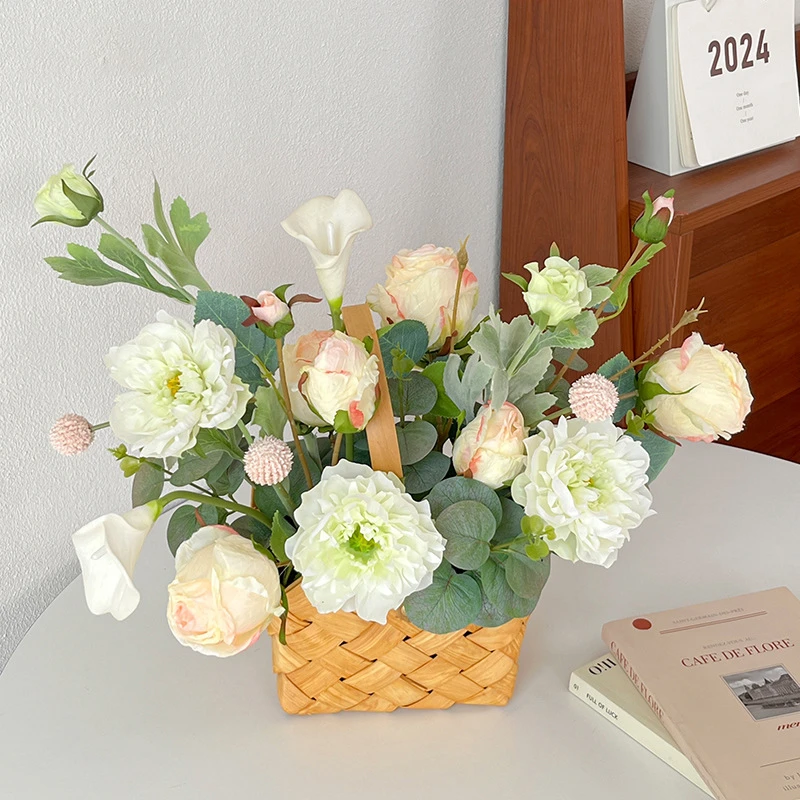 Ivory rose artificial flower basket arrangement in a woven basket with an upright handle, styled on a table top